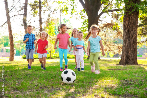 Cute little children playing with ball in park