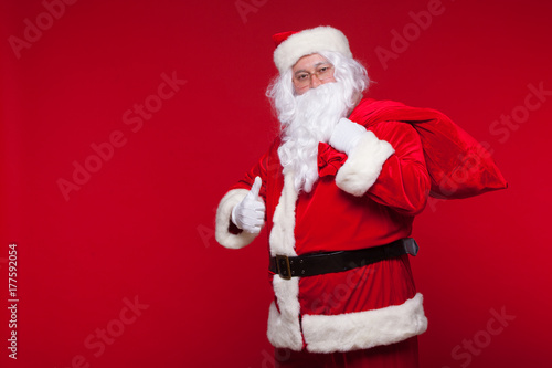 Christmas. santa claus with big bag on shoulder is on red background