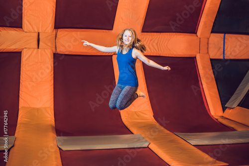 Young woman sportsman jumping on a trampoline in fitness park and doing exersice indoors