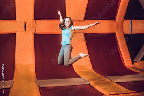 Young woman sportsman jumping on a trampoline in fitness park and doing exersice indoors