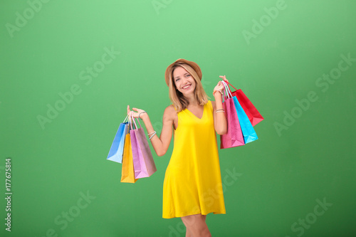 Beautiful woman with paper bags on green background