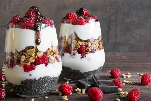 raspberry yogurt parfait in glasses with chocolate, granola and chia seeds