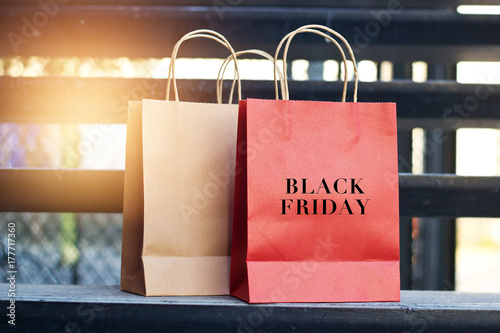 Black friday word on red and brown paper shopping bags placed on stairs outdoors on the mall background, business retail concept.