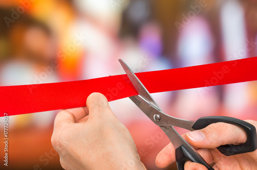 Hand with scissors cutting red ribbon - opening ceremony