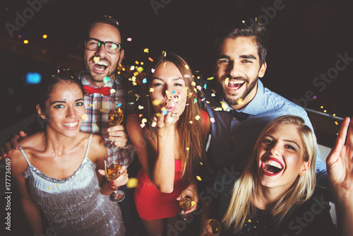 Group of people having a party, blowing confetti 