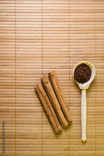cocoa in a wooden spoon and cinnamon tubes. Flat lay