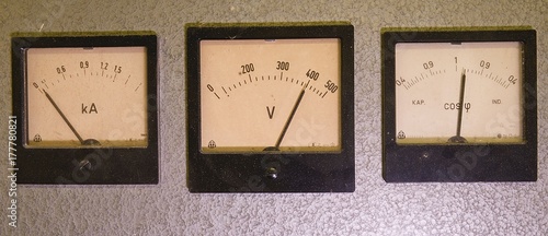 Three old analog instruments - Power factor meter, voltmeter and ampere meter isolated on grey background