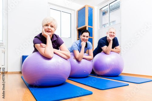 Physiotherapeutin zeigt Senioren Übungen mit Gymnastikball