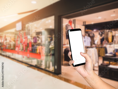 Hand holding and touching smartphone on fashion department store background blurred, Shopping centre mall