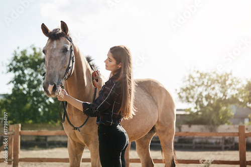 Young woman taking care of a horse. Broodmare managers are equine professionals with experience in managing the needs of mares and foals