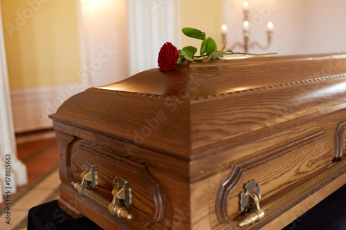 red rose flower on wooden coffin in church