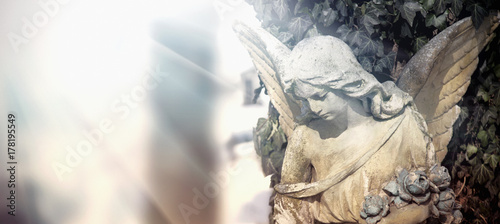 Vintage image of a sad angel on a cemetery. Ancient statue.
