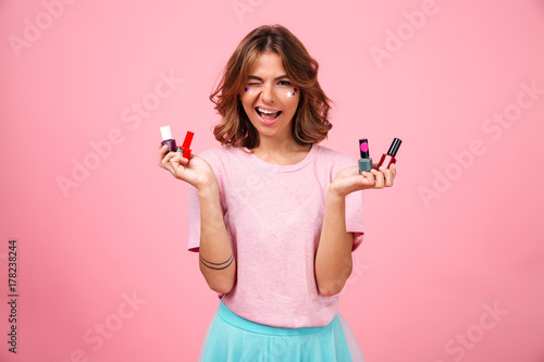 Cheerful emotional young woman holding nail polish