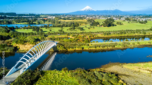 Aerial view on a beautiful bridge across a small stream with Mount Taranaki on the background. New Zealand