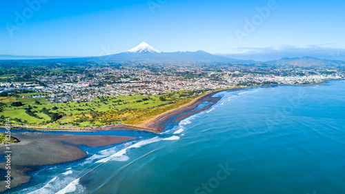 Aerial view on Taranaki coastline with a small river and New Plymouth and Mount Taranaki on the background. Taranaki region, New Zealand