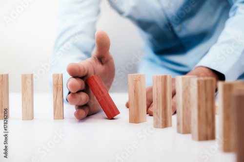 Businessman hand stop dominoes continuous toppled or risk with copyspace. Risk, Strategy, Planning management concept.