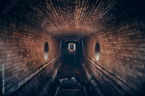 Red brick underground sewer tunnel with dramatic mysterious atmosphere