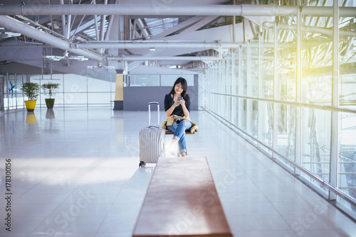 Beautiful Asian woman traveler using mobile phone in airport, Lifestyle using cell phone connection concept,while waiting for her flight
