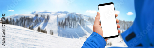 Man hand holding modern smartphone with isolated screen, snowy mountain in background