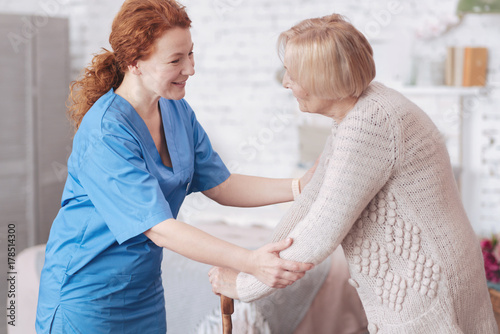 Positive caregiver having pleasant conversation with retired lady