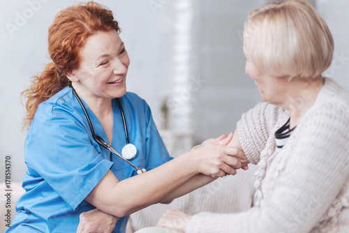 Positive minded nurse taking care of elderly woman at home