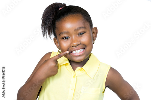 Cute african girl pointing with finger at teeth.