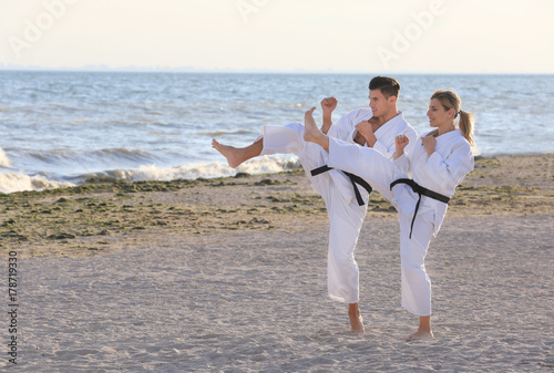 Young man and woman practicing karate outdoors