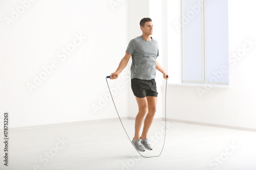 Young man skipping rope indoors