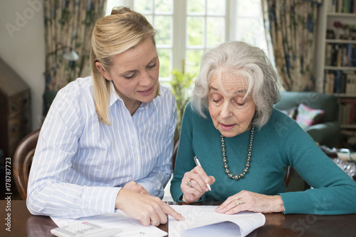 Woman Helping Senior Neighbor With Paperwork