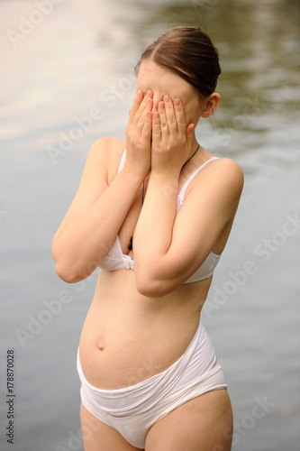 A semi-nude Caucasian girl resting on the lake during pregnancy. The concept of a healthy lifestyle. Lingerie for pregnant women.