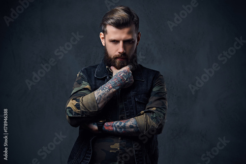 Portrait of bearded tattooed hipster male dressed in a military 