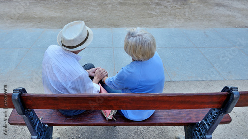 Pair of older people sitting on bench.