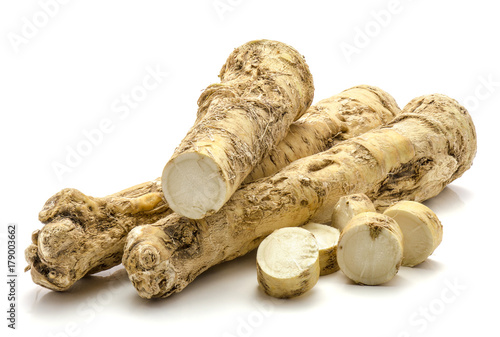 Two whole one half and sliced circles of fresh horseradish root isolated on white background