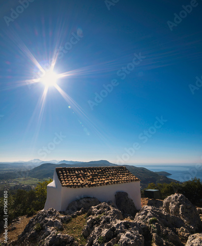 Old small white chapel, Ai Symeon, in mountains under clear blue sky. Doukades, Corfu, Greece.