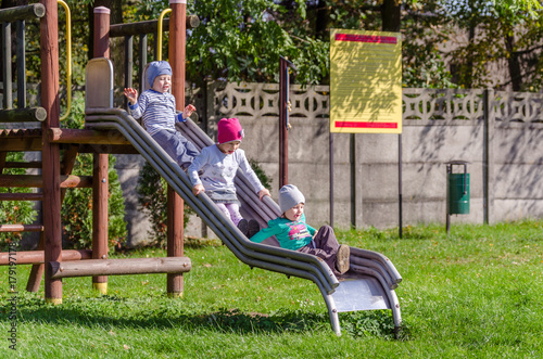 Rodzeństwo dzieci bawi się na planu zabaw w jesienny słoneczny dzień.