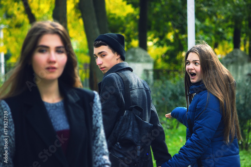 Disloyal man walking with girlfriend and looking amazed at another seductive girl