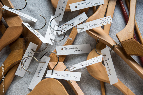 Pile of wooden hangers with day and occasion tags 