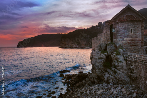 old wall and tower of fortress near sea and unreal sunset