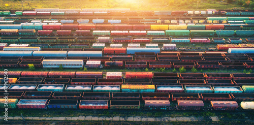 Top view of cargo trains. Aerial view from flying drone of colorful freight trains on the railway station. Wagons with goods on railroad. Heavy industry. Industrial conceptual scene with trains.