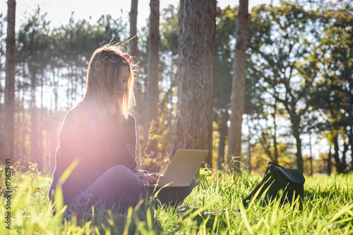 woman sitting in forest with laptop enjoying late afternoon sun and some quiet time