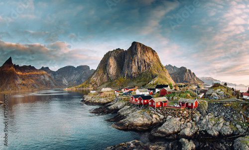 Norwegian fishing village at the Lofoten Islands in Norway. Dramatic sunset clouds moving over steep mountain peaks