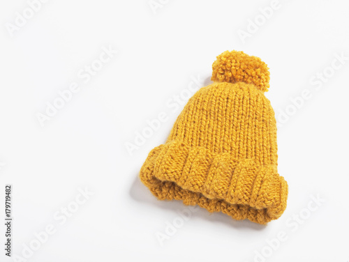 Mustard knit beanie hat with big pom pom isolated on white background. Copy space.