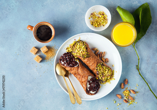 Cannoli with ricotta, chocolate and pistachios. Italian pastries of the Sicily . classic breakfast with orange juice and coffee