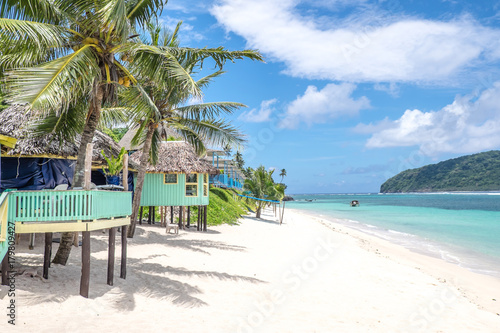 View along Lalomanu Beach, Upolu Island, Samoa, of colorful Samoan beach fale huts that are an alternative to hotel or resort accommodation