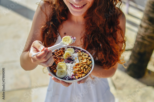 Acai bowl woman eating morning breakfast at cafe. Closeup of fruit smoothie healthy diet for weight loss with berries and oatmeal. Organic raw vegan healthy food.