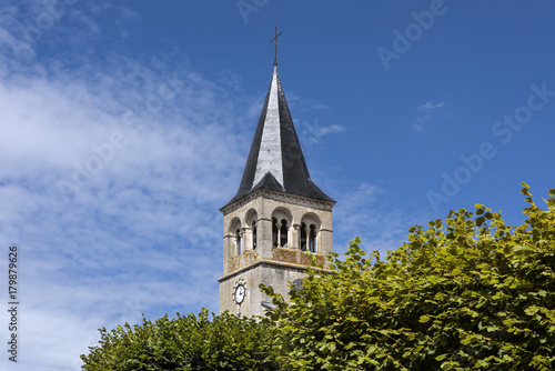 France, Cormatin: Steeple with tower clock, green trees and blue sky