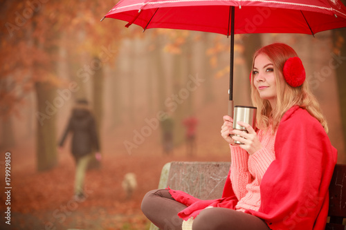 Girl in autumn park enjoying hot drink
