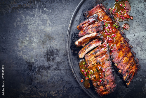 Barbecue pork spare ribs with fruit relish as top view on an old rustic board with copy space