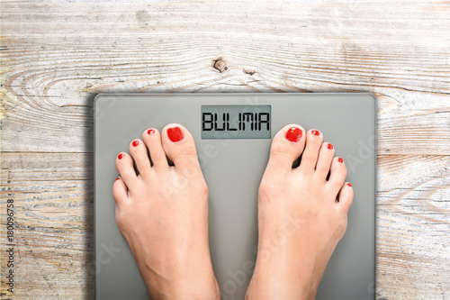 Health and care concept with bulimia word on bathroom scale while a woman is weighting