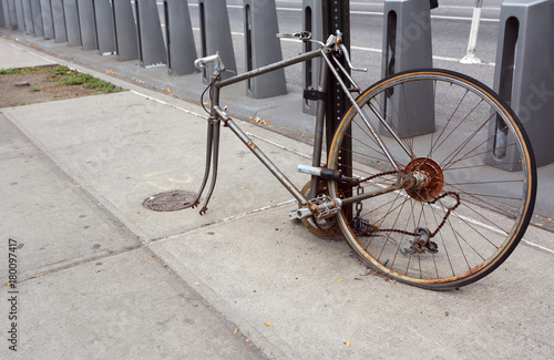 Broken, rusty bicycle locked to a metal pole